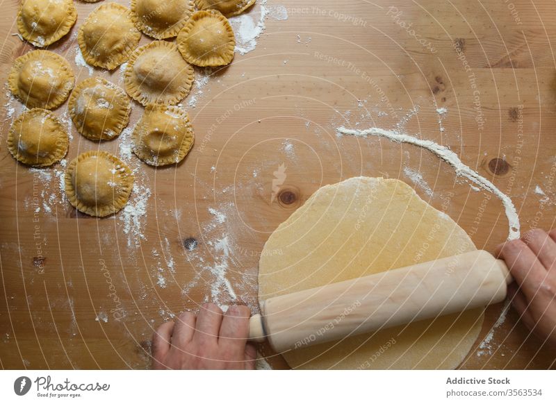 Crop male cook rolling dough on table with ravioli rolling pin prepare circle raw person round wooden process kitchen food cuisine culinary homemade dish