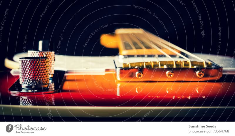 Close up of an Electric Guitar with a sunburst paint job musical instrument electric guitar vintage wood fretboard neck string controls knob colorful orange