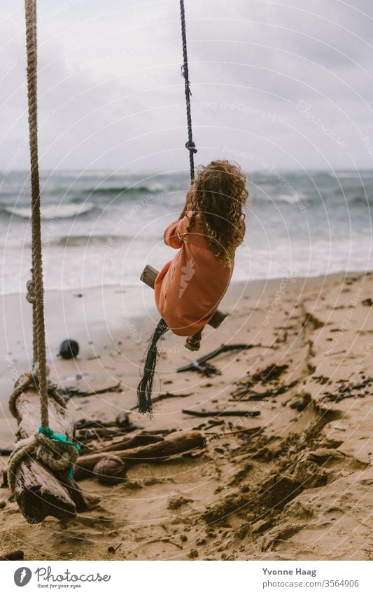 Girl sitting on a swing and swinging towards the sea Hawaii Hibiscus To swing Rocking Joy Playing Exterior shot Colour photo Swing Playground Infancy Day Child