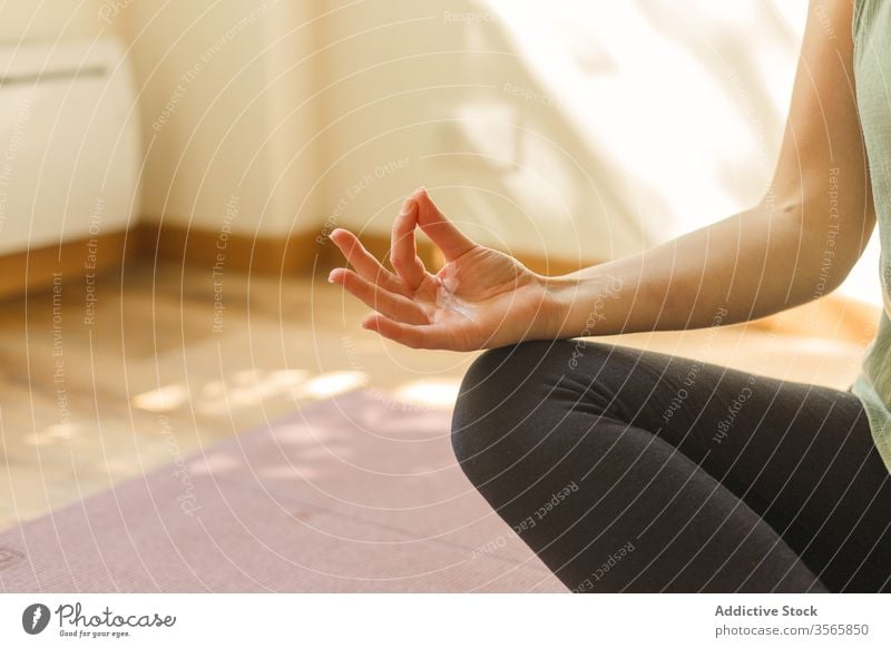 Crop woman in Lotus pose on mat yoga lotus pose mudra gesture exercise padmasana sportswear female calm practice mindfulness silent serene tranquil focus