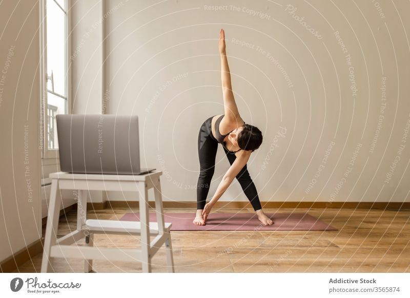 Fit woman stretching back on yoga mat at home - a Royalty Free