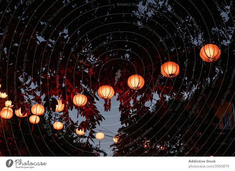 Asian paper lanterns glowing on street in evening illuminate asian festive oriental culture tradition hang decoration creative vietnam luminous garland dark