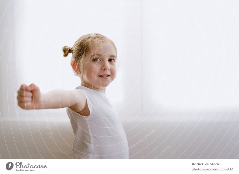 Happy girl doing morning exercises in living room little stretch arm kid warm up content happy adorable smile delight child cheerful optimist cute outstretch