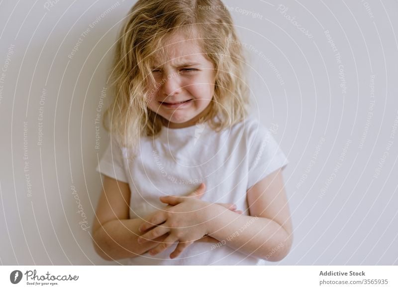 Little girl crying in studio weep naughty little child arms folded whine casual sad frown disappoint kid childhood face expression adorable cute t shirt blonde