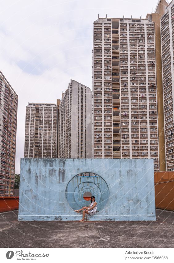 Woman near walls with tunnel in Hong Kong woman passage street installation city unusual creative summer female shek kip mei hong kong round shape outfit dress