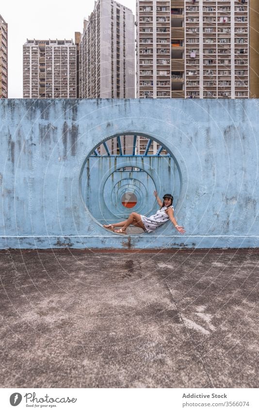 Woman sitting near walls with tunnel in Hong Kong woman passage street installation city unusual creative summer female shek kip mei hong kong round shape