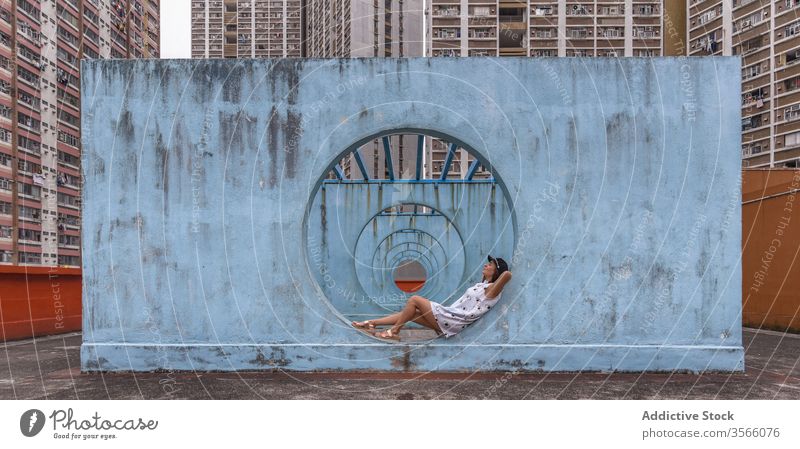 Woman resting near walls with tunnel in Hong Kong woman passage street installation city unusual creative summer female shek kip mei hong kong round shape