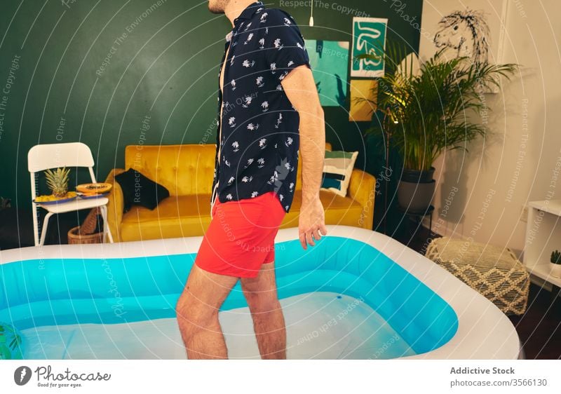 Man in inflatable pool during home party man stay at home summer apartment creative self isolation having fun water male shorts shirt social distancing outfit