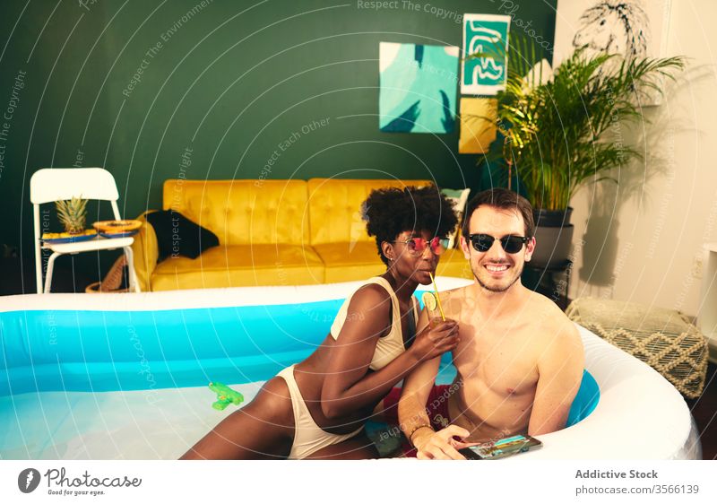 Content multiethnic couple resting in inflatable pool party stay at home content having fun self isolation in love social distancing water together multiracial