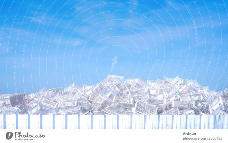 Pile of white plastic basket at factory outdoor warehouse. Many of empty plastic basket against blue sky and white clouds. Basket for store products. Stacked of plastic crates. Cargo and shipping.