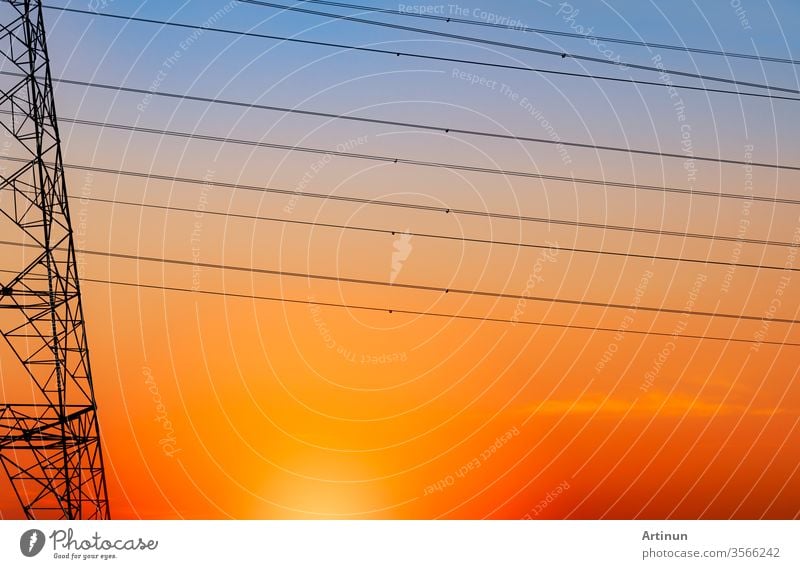 Silhouette high voltage electric pylon and electrical wire with an orange sky. Electricity poles at sunset. Power and energy concept. High voltage grid tower with wire cable at distribution station.