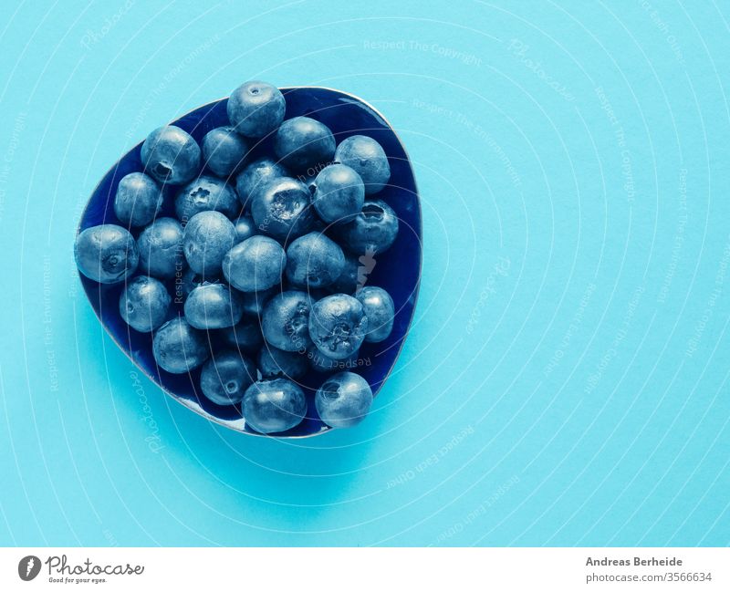 Tasty organic blueberries on a blue paper background antioxidants detox top view wet juice health vitamin nutrition dieting heap closeup harvest bio crop eating