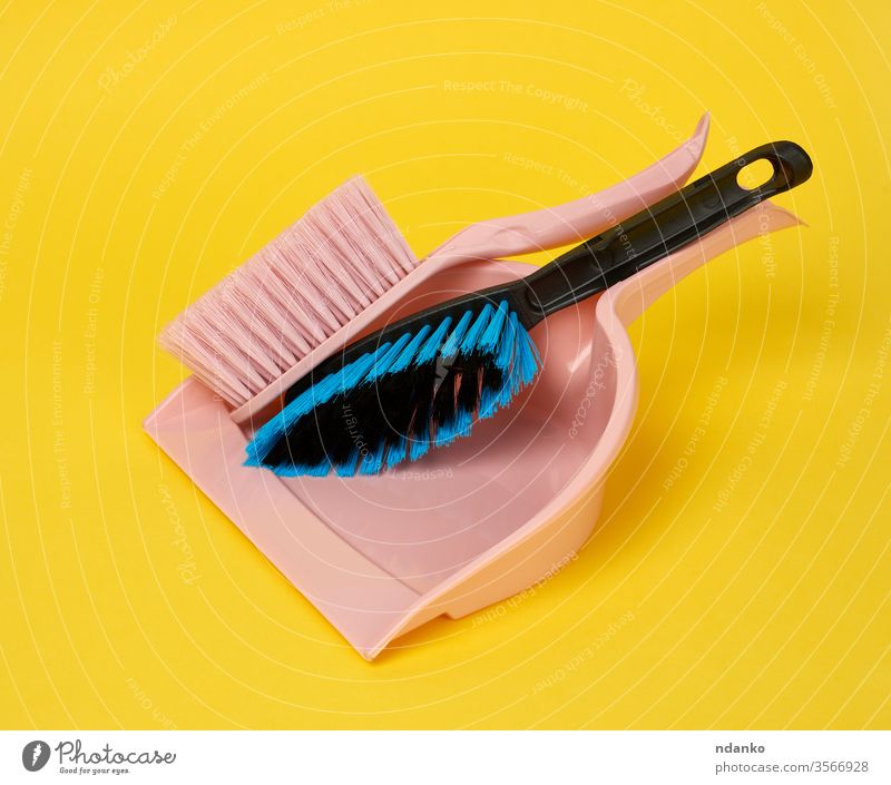 pink plastic scoop and cleaning brush on a yellow background shovel single studio sweep chore cleaner cleanup clear closeup color domestic dust duster dustpan