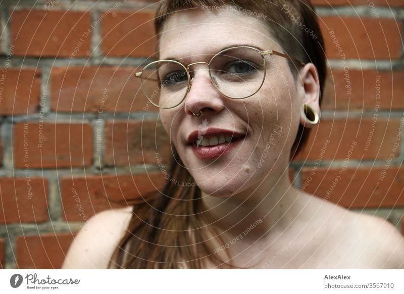 Portrait of a young woman in front of a brick wall Woman Youth (Young adults) already Strong Alternative great Piercing Skin Intensive Looking look watch Stand