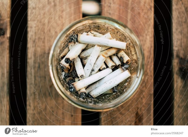 A round glass as ashtray with many cigarette butts in it from bird's eye view Ashtray dumb cigarettes Cigarette Butt Smoking homemade Roll-up cigarette Nicotine