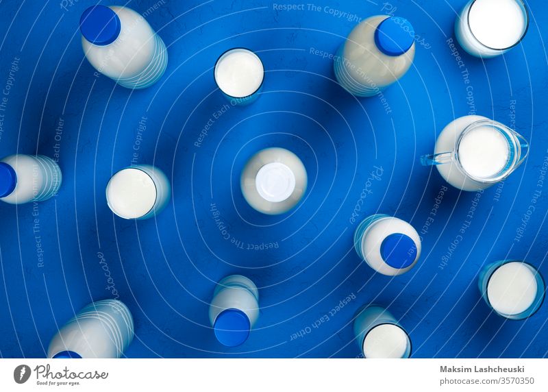 Collection of bottles and glasses with milk on blue background, top view different type dairy product set sour cream bowl creamer white pattern above table food