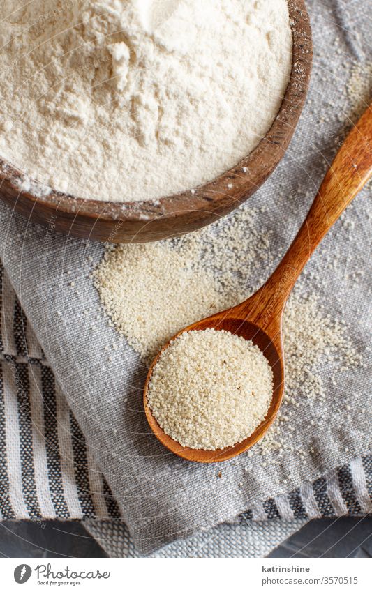 Raw fonio flour and seeds with a spoon on grey napkins Alternative dry uncooked bowl wooden background close up copy space african cereal food nutriment organic