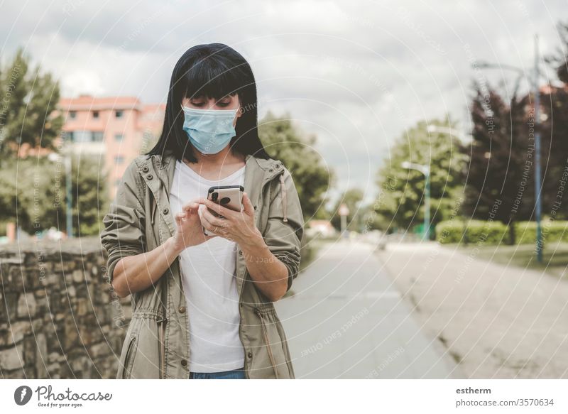 woman wearing medical mask With his smartphone on the street coronavirus young woman epidemic pandemic quarantine covid-19 app mobile technology portrait
