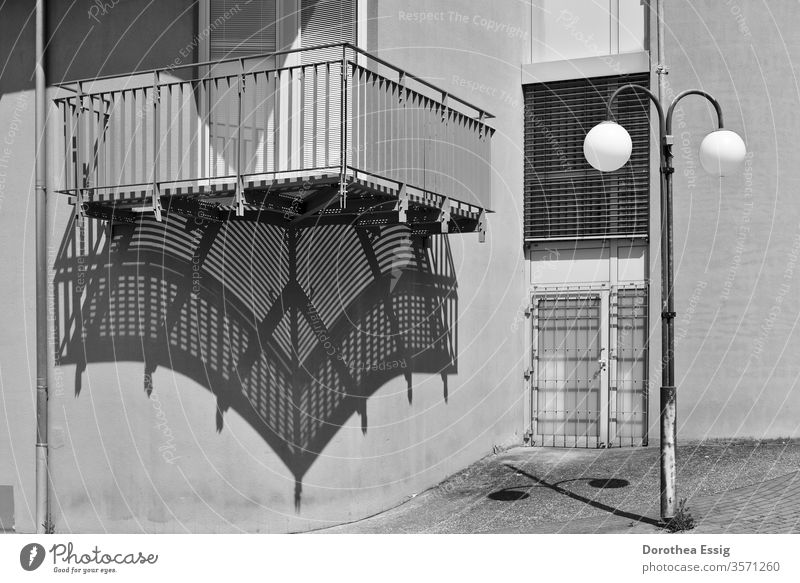 Balcony and street lamp throw shade Shadow Part of a building House (Residential Structure) Wall (barrier) Black and white photo Exterior shot Deserted Sun Day