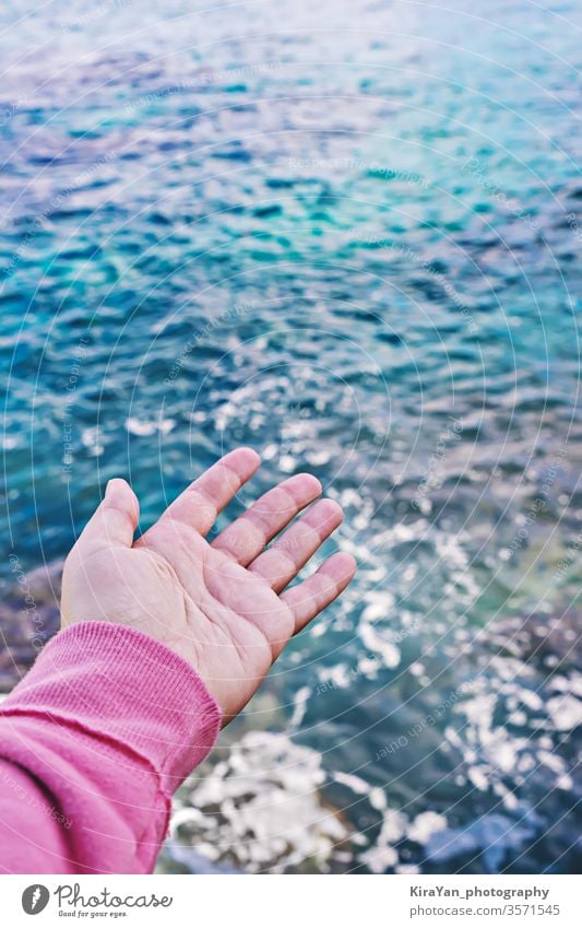 Female hand with an open palm reaches for surface of the water world oceans day hope man woman sea blue concept pov touch safe protect restore protection