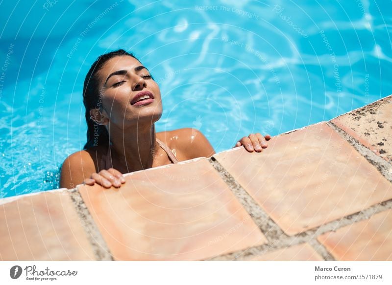 Mixed race young woman relaxing in water at swimming pool mixed race beautiful attractive bikini tanned skin girl sunbathing vacation model lifestyle resort