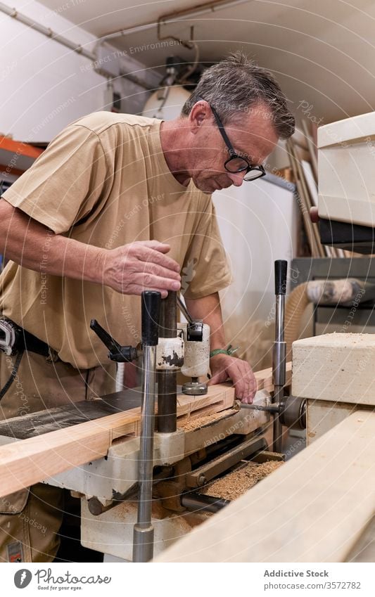 Diligent carpenter drilling timber in modern workroom carpentry woodwork processing handcraft man workshop workplace equipment joiner lumber plank craftsman