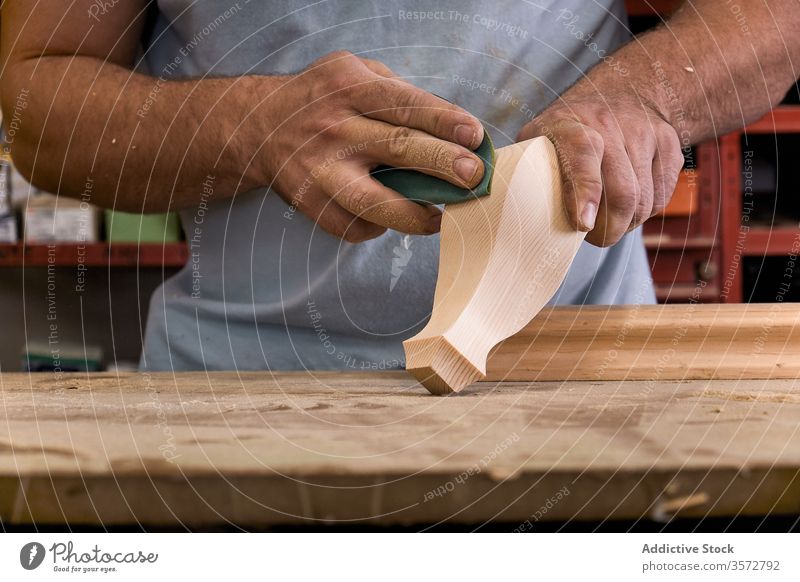 Artisan polishing wooden detail using sandpaper in carpentry workshop artisan control woodwork hand master man tool handwork craftsman workroom handicraft