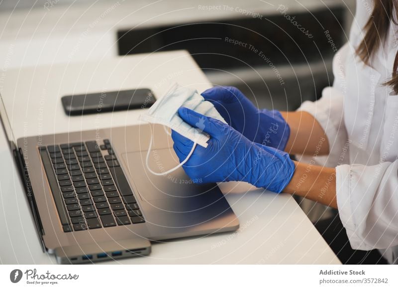 Woman with protective mask and gloves using laptop coronavirus home work remote workplace hand gadget device safety covid covid 19 covid19 pandemic epidemic