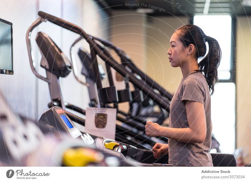 Young ethnic sportswoman running on treadmill while training in modern gym cardio exercise athlete healthy workout fitness slim young active wear wellness