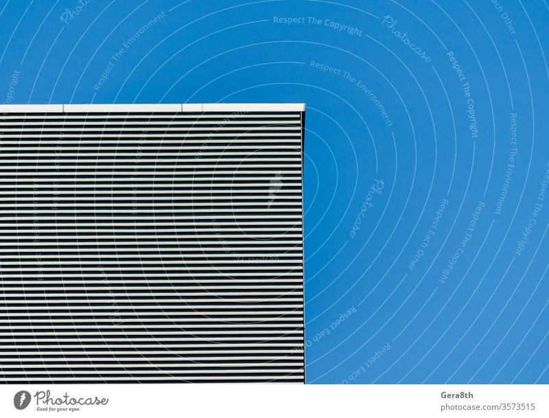 striped wall of a gray tall building against a blue clear sky abstract abstract background angle architecture black blank clean effect empty gelmetry house