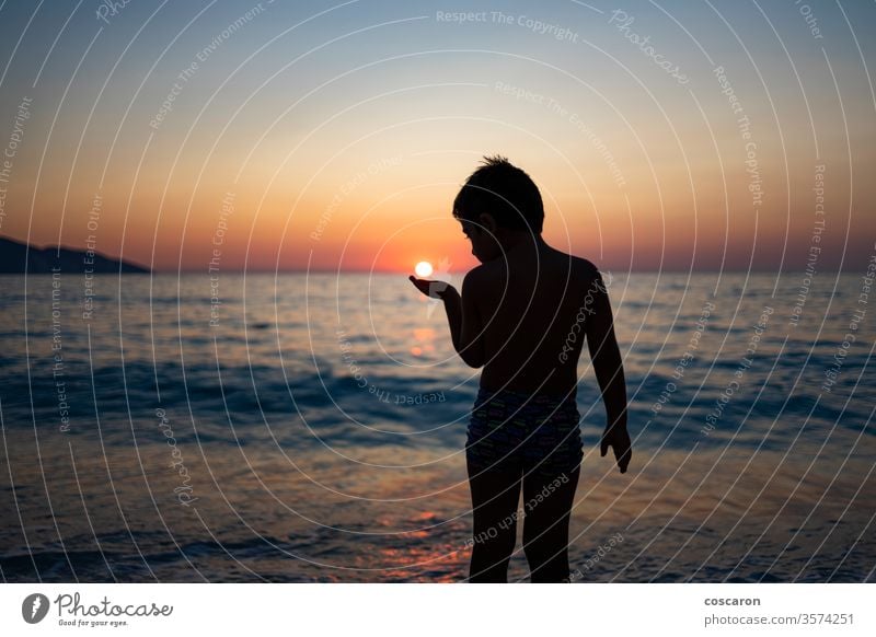 Little kid playing with the sun on the beach at sunset active beautiful boy carefree cheerful child childhood coast coastal evening fun greece hand happiness