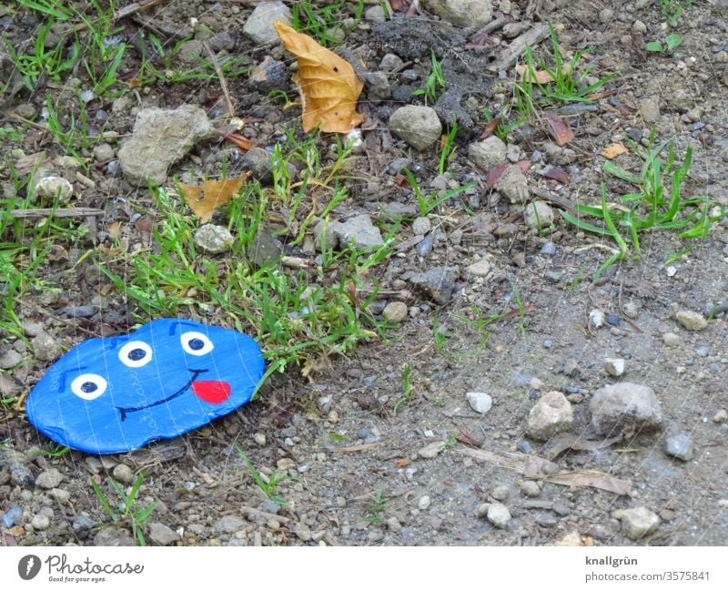A blue lucky stone with a funny monster face with three eyes and tongue stuck out by the wayside Lucky Stones Monster Joy Wish stone Painted Leisure and hobbies