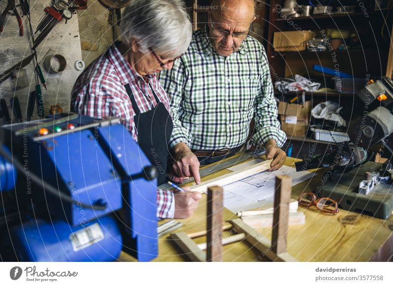 Senior couple in a carpentry senior carpenter workshop working wood mature business caucasian home retirement worker artisan cabinetmaker concentration