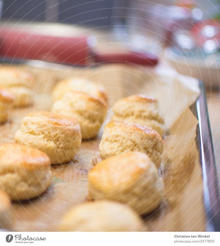 Freshly baked delicious scones lie on the baking tray. In the background you can see a red dough roll and glass vessels Baked goods Food Dough Cake