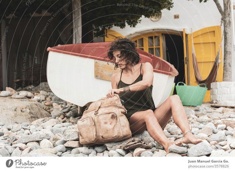 A beautiful female Latina sitting beside her bag in the seashore woman girl beauty young pretty attractive people adult white natural person travel beach