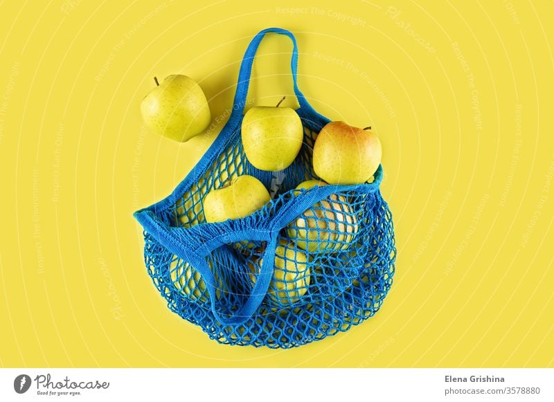 Ripe apples in a blue string bag on a yellow background. zero waste eco bag mesh bag cotton ecology concept ecological natural reusable recycle lifestyle