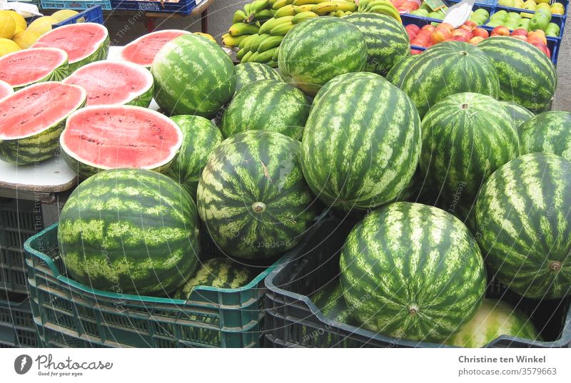 Watermelons in baskets at a Mediterranean market stall. In the background bananas and apples Melon fruits Nutrition Summer Food Delicious Juicy Bananas Round
