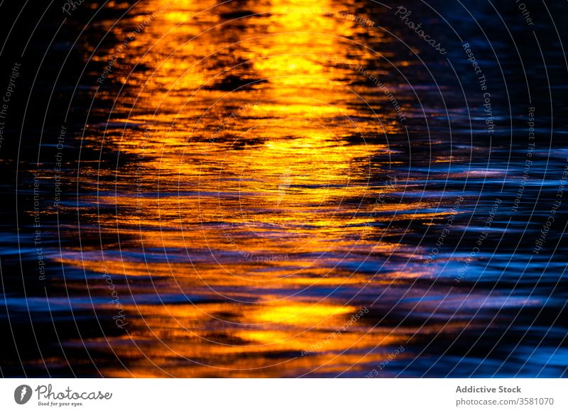 Light reflected in dark water light reflection ripple texture sunset dusk background nature night glow shiny illuminate abstract bright beam surface colorful