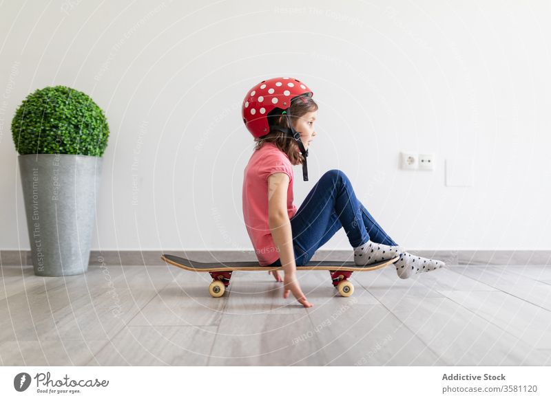 Happy preteen girl riding skateboard at home game entertain fun child play decor longboard helmet kid dream stay at home having fun safety social distancing