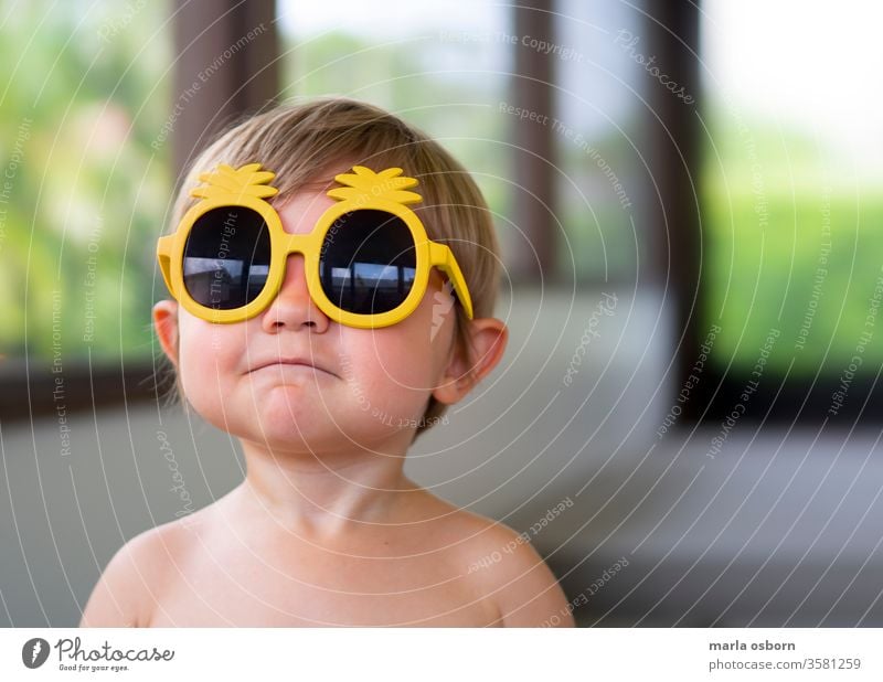 Little boy wearing yellow pineapple sunglasses on back porch toddler wearing sunglasses happy sunny home house outdoor florida youth young child caucasian funny