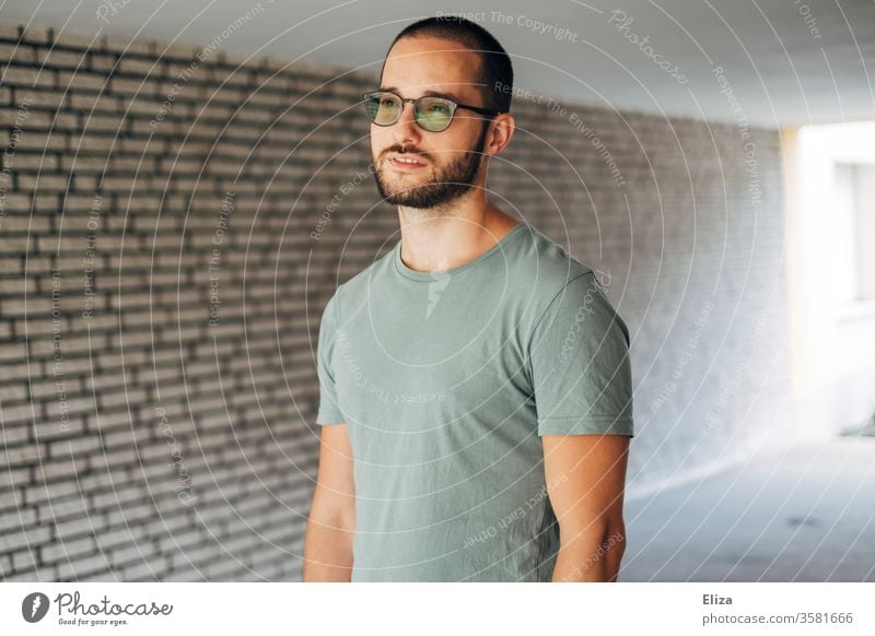 A man in a T-shirt stands in an underpass and looks thoughtfully into the distance. Vision. vision Meditative Man Bright Underpass visionary Wall (building)