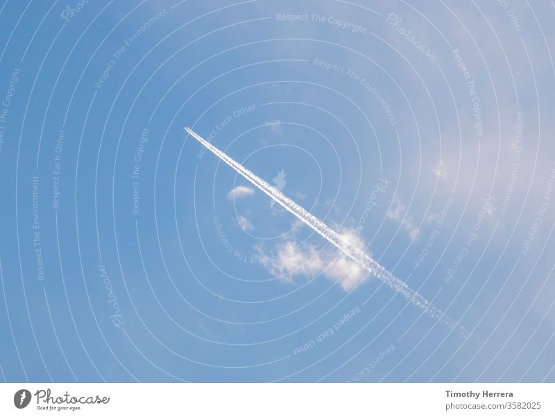 An airplane leaving behind a condensation trail or contrail. sky blue sky travel sky trail vapor trail clouds flying vacation travel leisure freedom