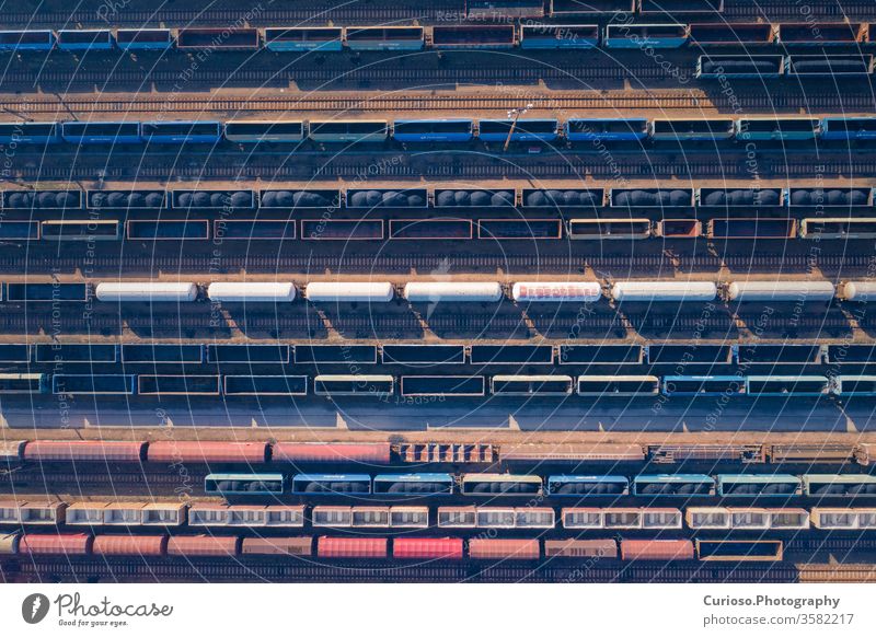 Aerial view of colorful freight trains on the railway station. Wagons with goods on railroad. Heavy industry. Industrial conceptual scene with trains. Top view. Photo captured with drone.