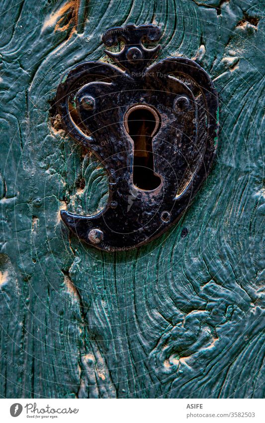 Old heart shaped door lock on a blue wooden door detail close up old rustic iron wrought painted front rural closed black ancient antique architecture vintage