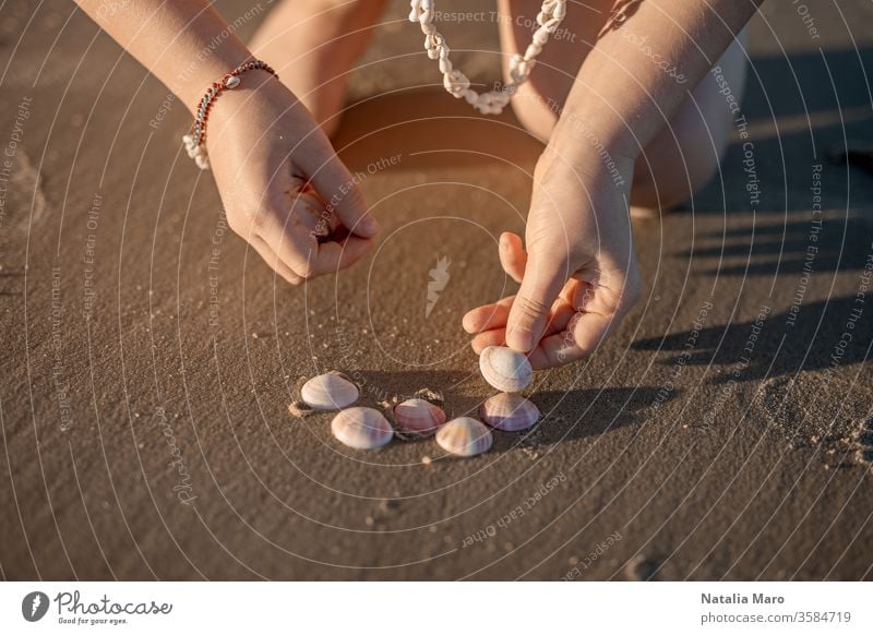 Little girl's hands creating a heart from seashells on the ocean sandy beach. child kid love seashore summer sun outdoor nature lifestyle toddler travel
