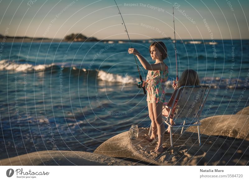 Two little girls are fishing in ocean surf at sunset. Summer leisure, hobby and fun for kids. people vacation person young recreation water caucasian family