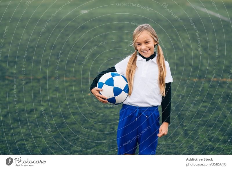 Happy young female player with ball in football arena at sports stadium girl soccer field uniform happy child kid club childhood athlete equipment smile preteen