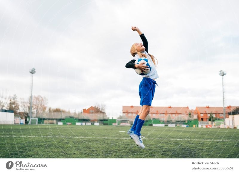 Happy young female player rejoicing in success while playing football at sports stadium girl soccer win kid celebrate goal victory happy field triumph rejoice