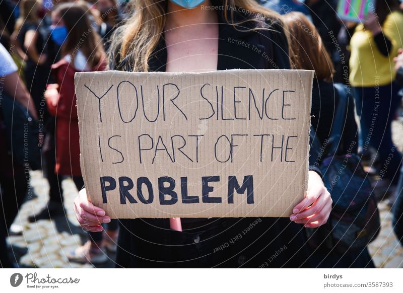 Your silence is part of the problem. A young woman carries a sign with the inscription, " your silence is part of the problem ". Civil courage against police violence, violence, discrediting, sexual assault and violence in general.
