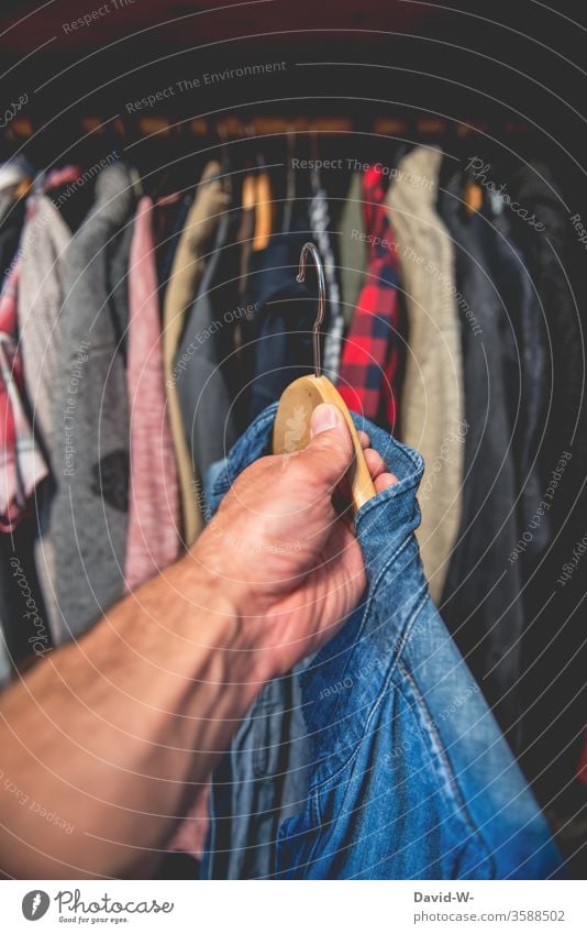 a blue shirt from the wardrobe by hand garments Attract Closet Hallstand Shirt Grasp Decide Clothing Fashion Interior shot Style hang Hanger Colour photo